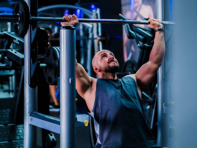How Creatine Became an Anti-Aging and Longevity Essential 3 A man doing shoulder presses in the gym.